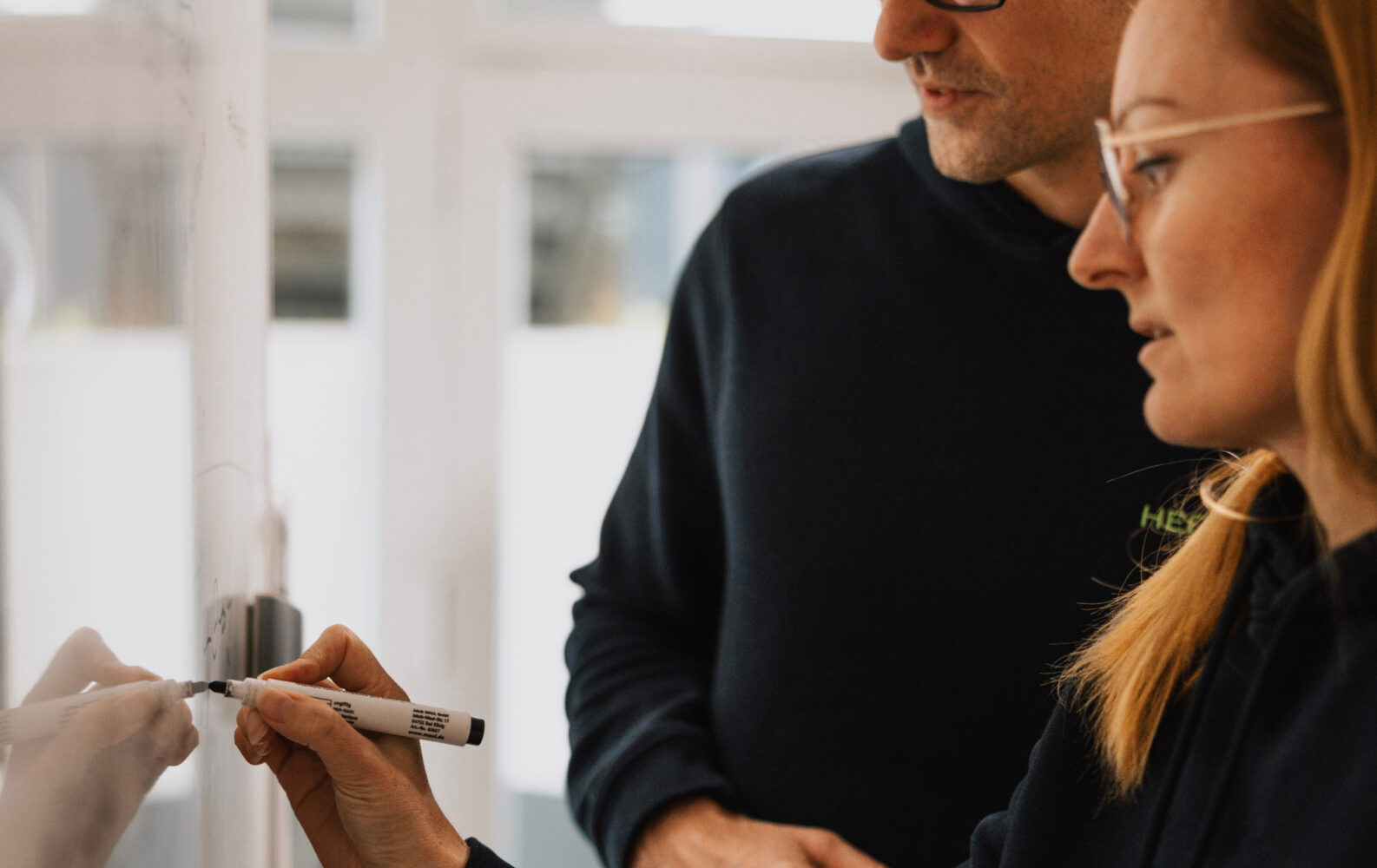 Zwei Personen zeichnen etwas am Whiteboard